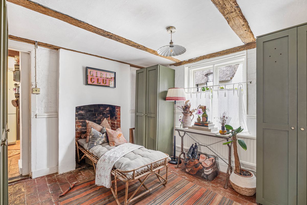 The second reception room, fitted with green wardrobes, with a brick fireplace and a daybed