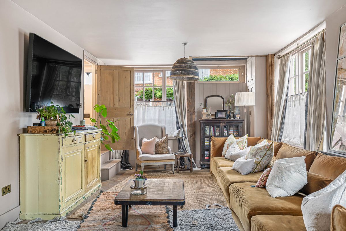 The sitting room, light from windows on three sides, with a deep sofa and a fireplace